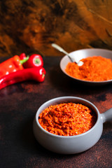 Ajvar Balkan appetizer of baked peppers.  Serbian and Balkan cuisine. Ajvar in a bowl, paprika powder and fresh peppers on the background. Golden rich color background. Vertical. Space for text