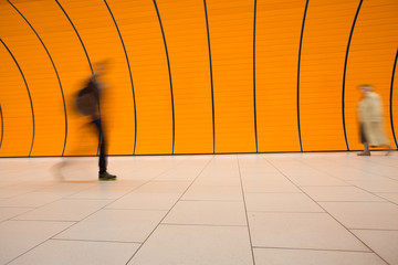 People rushing through a subway corridor (motion blur technique is used to convey movement)