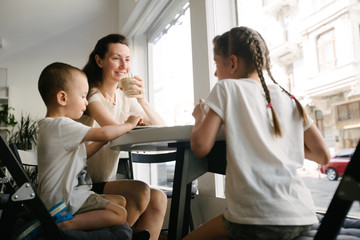 Mother with children drinking hot chocolate and latte at a local coffee shop. They are smiling and having fun.