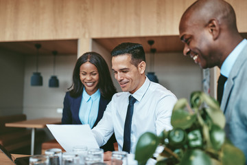 Three diverse businesspeople laughing while going over documents
