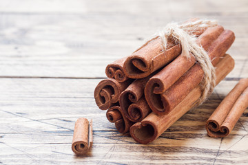 Several cinnamon sticks tied with thread on a wooden background. Copy space. Selective focus.