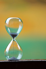 Hourglass on wooden and colorful background