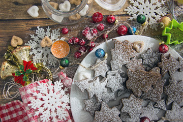 Fototapeta na wymiar Christmas sweets and decorations on table Top view of plate of fresh gingerbread cookies with powdered sugar placed on wooden table amidst various Christmas decorations