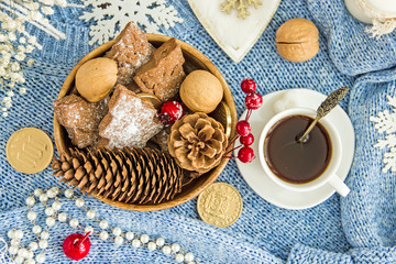 Blue knitted sweater, white cup with coffee, homemade cookies, white candles, snowflakes on a light wooden table, top view, flat lay. The concept of a New Year card, Christmas holidays. Save space