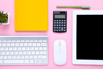 Tablet and computer keyboard with office supplies on pink background