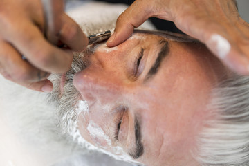 Naklejka premium Barber shaving mustache to client in salon