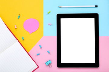 Tablet computer with office supplies on colorful paper background