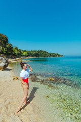 sexy woman in red swimsuit and white t-shirt at sea beach