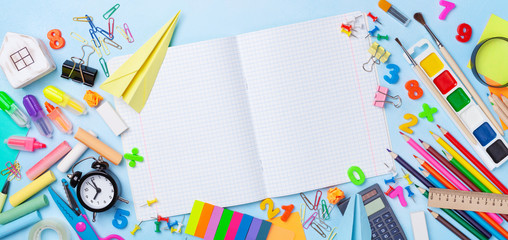 School supplies and stationery with open notebook on blue table top view. Education, learning and...
