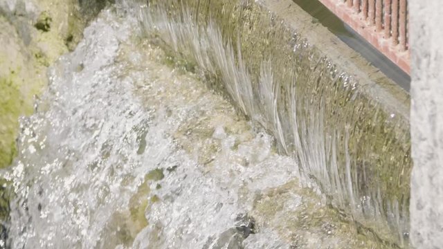 Close up of whater in slow motion flowing out of a wall opening