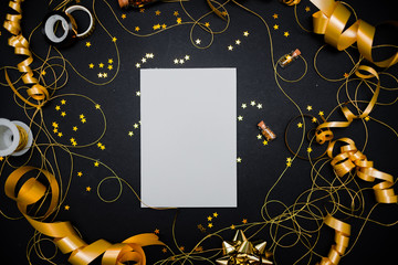 Gift box with golden bow on black background with decoration and sparkles. Festive concept copyspace top horizontal view