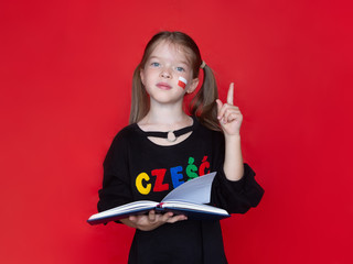 little girl in a black sweatshirt, on her sweatshirt the word Hello in Polish raised her finger up, holds a notebook or book in her hand, Advertising concept for learning Polish