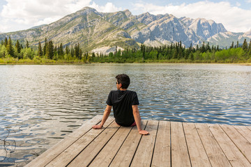 Man enjoying the view by a lake with mountains in the background