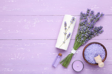 Lavender flowers with oil, salt and candle on puple wooden table