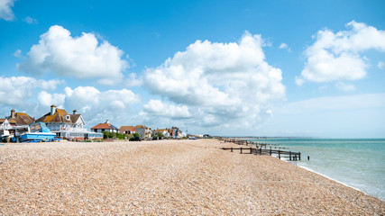 Pevensey Bay, East Sussex, England. Traditional beach houses along the coastline of the south coast of England on a bright summers day.