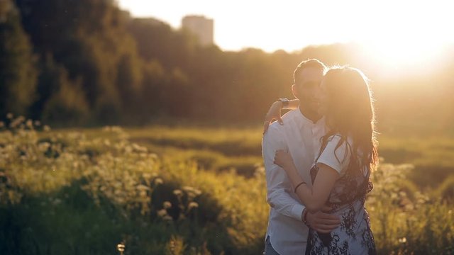 Young man and woman strolling in a meadow at sunset in summer. Romance. Summer love togetherness joy romantic memories forever together concept