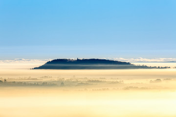 Foggy morning view with a hill above the fog