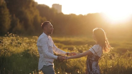 Young man and woman strolling in a meadow at sunset in summer. Romance. Summer love togetherness joy romantic memories forever together concept