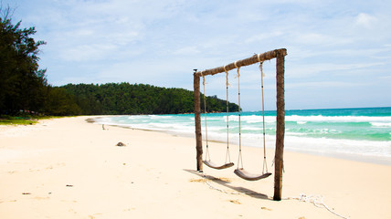 Swing on the beach with blue sea on the background