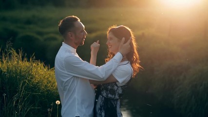 Couple in a park by the river in summer at sunset. Love, relationship, kiss