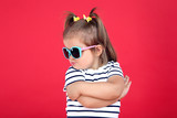 Cute little girl in sunglasses on red background
