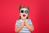 Cute little girl in sunglasses on red background