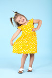 Cute little girl in yellow dress on blue background