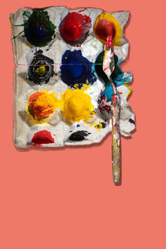 Color palette, full with mixed fresh colours in an art studio, made from an used egg card board container. Painting equipment in action with a popular colour background.
