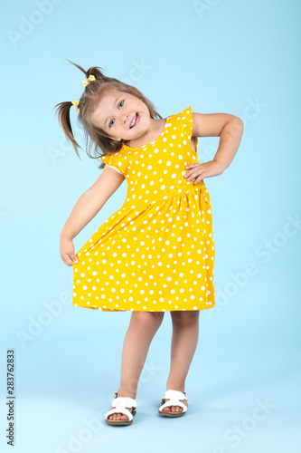 Cute little girl in yellow dress on blue background