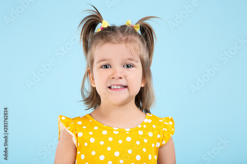 Cute little girl in yellow dress on blue background