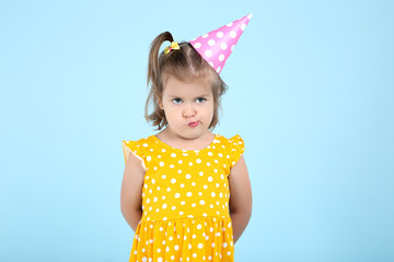 Cute little girl in birthday cap on blue background