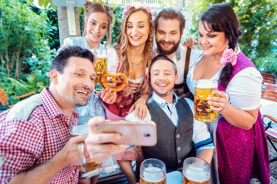 Cheerful group of friends taking a selfie in Bavarian beer garden