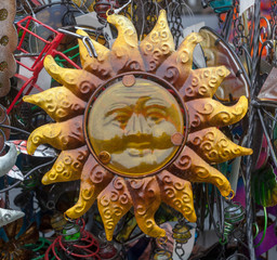 Happy golden metal sun intended as garden wall art.