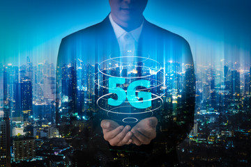 Double exposure image of Businessman hand holding 5g hologram and internet of things on city background. Business man creating 5g with his hand.