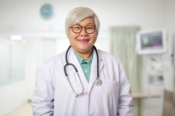 Senior Asian doctor woman with smiling  face on the background of the modern hospital