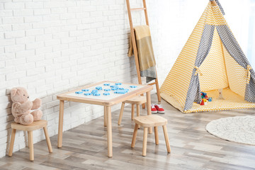 Fototapeta na wymiar Cozy kids room interior with table, stools and play tent