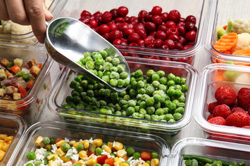 Woman scooping peas from box, closeup view