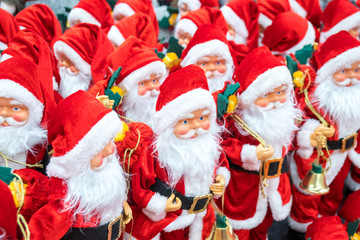 A lot of Santa Clauses standing on the shelf of the souvenir shop.