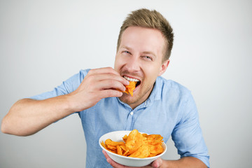 young handsome man eats chips on isolated white background