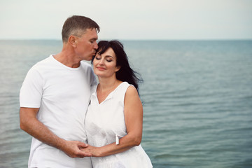 Happy mature couple spending time together on sea beach. Space for text