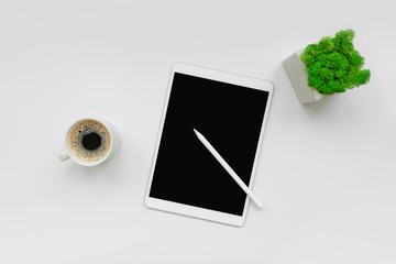 Tablet, pencil and cup of coffee on white desk. Top view. Copy space. Mock-up