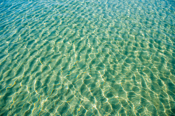 Fototapeta na wymiar Tropical blue-green waters background in shallow seas with small waves in bright sunlight