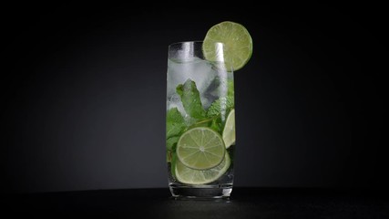 Cold cocktail with lime and mint on black background.