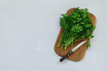 Cutting boar with fresh green parsley and dill or fennel on gray wooden board. Top view. Copy space. Harvesting concept