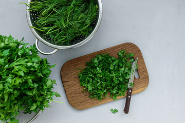 Chopped fresh green parsley and dill or fennel on cutting boar on gray wooden table. Top view. Copy space. Harvesting concept