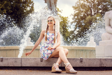 Woman sitting on the edge of a fountain on a hot summer day