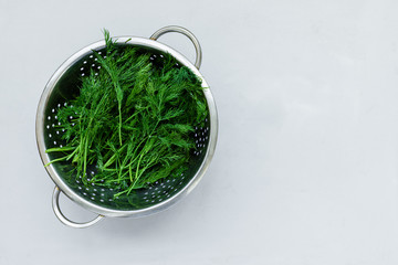 Bowl of fresh green dill or fennel on gray wooden board. Top view. Copy space. Harvesting concept