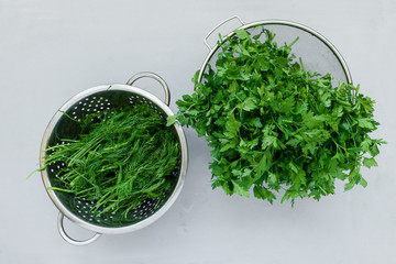 Bowls of fresh green dill or fennel and parsley on gray wooden board. Top view. Copy space. Harvesting concept