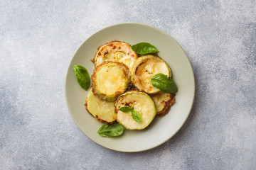 Slices of fried zucchini in batter with garlic and Basil on a plate.