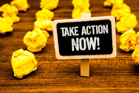Handwriting text writing Take Action Now Motivational Call. Concept meaning Urgent Move Start Promptly Immediate Begin White text black paint wooden board clip desk yellow paper notes warning